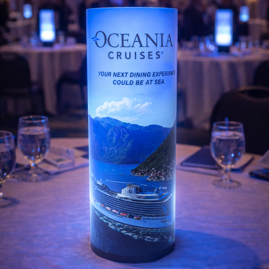 Oceania Cruises promotional bottle on a table with glasses and a blurred event background